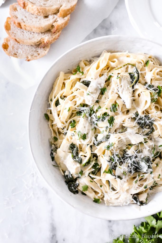 This Spinach Artichoke Fettuccini is made with fresh fettuccini topped with a creamy sauce filled with marinated artichoke hearts and spinach and topped with fresh parsley and grated parmesan.