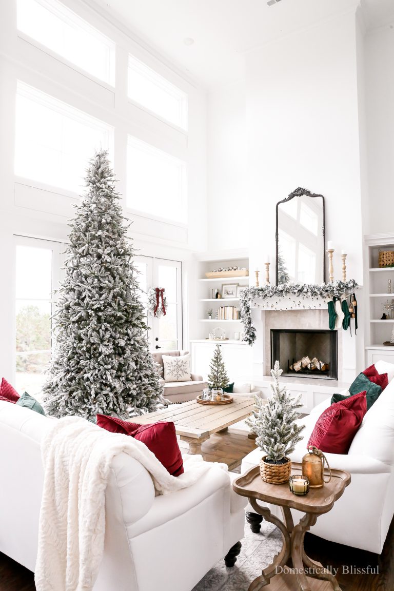 Cozy Classic Christmas Living Room Decor with a 12-foot flocked Christmas tree, flocked garland, and flocked wreaths, with wine red and forest green accents.