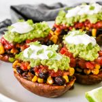 These Loaded Black Bean Taco Sweet Potatoes are covered in seasoned black beans and corn and topped with cheese, sour cream, salsa, guacamole, cilantro, and a squeeze of lime.