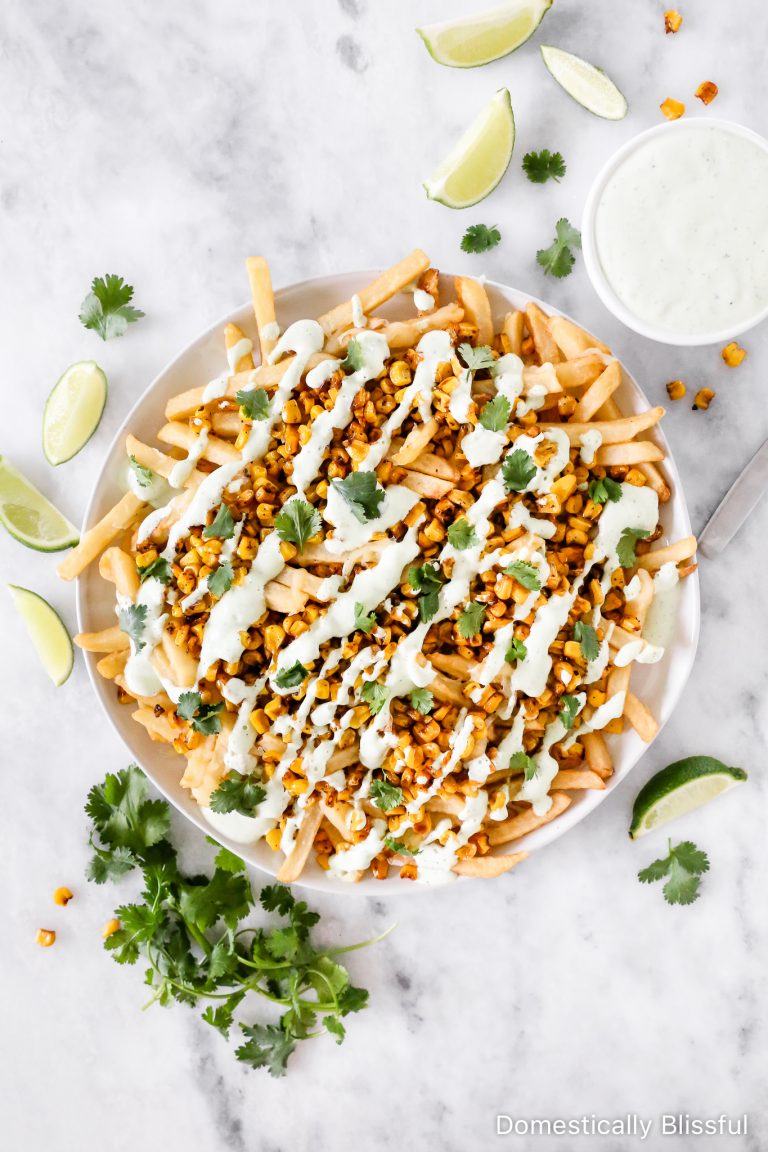 These Mexican Street Corn Fries are super easy to make with a base of crispy fries and melted cheese, topped with roasted corn, drizzled with cilantro cream sauce, and a squeeze of lime.