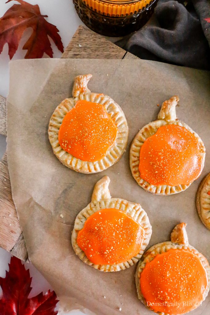 These Homemade Pumpkin Pop Tarts are made with pie crust and have a sweet pumpkin filling topped with orange icing and sprinkles, making them perfect for a fall party or Thanksgiving brunch.
