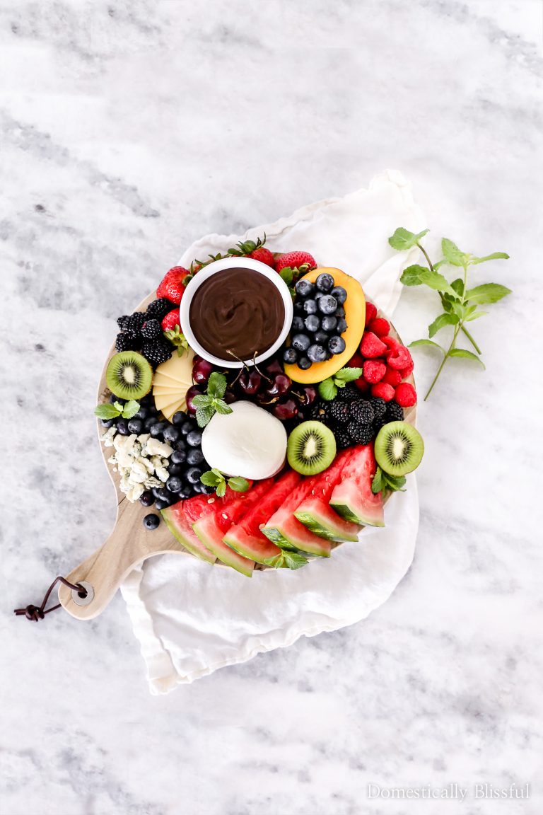 This Summer Fruit Plate is loaded with watermelon, cherries, kiwi, mango, blueberries, raspberries, blackberries, melted dark chocolate, & a variety of delicious cheeses.