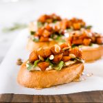 This Whipped Goat Cheese Butternut Squash Bruschetta begins with sliced toasted baguette, topped with whipped goat cheese, arugula, roasted butternut squash, honey, and pumpkin seeds.