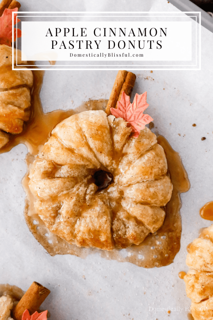 These Apple Cinnamon Pastry Donuts are filled with fresh apple slices, surrounded by puff pastry, covered in cinnamon sugar, drizzled with caramel sauce, and topped with a cinnamon stick and edible maple leaf.