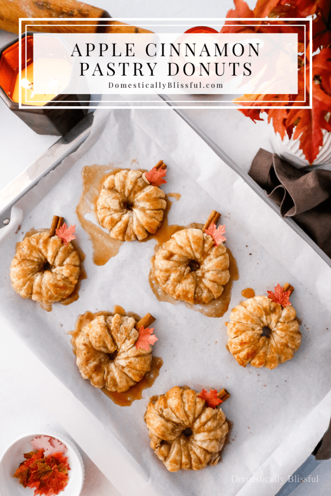 These Apple Cinnamon Pastry Donuts are filled with fresh apple slices, surrounded by puff pastry, covered in cinnamon sugar, drizzled with caramel sauce, and topped with a cinnamon stick and edible maple leaf.